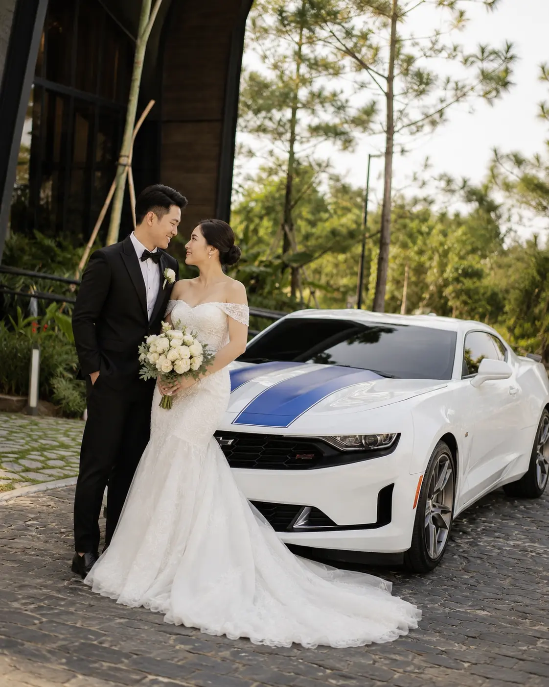 Bride and groom beside their white Chevrolet Camaro RS bridal car with blue rally stripes